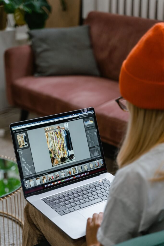 Woman with knit hat shopping online for clothes on a laptop from her cozy living room.
